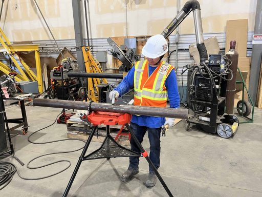 Rotaflow apprentice cutting pipe on a stand in the fabrication shop